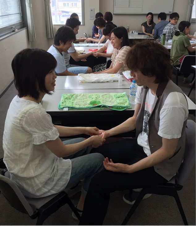 育児休業復帰支援事業で夫婦がハンドマッサージを行っている様子。5回の連続講座のうちの１回。復帰に向け夫婦で考える。